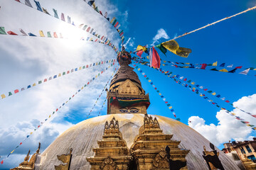 Nepal. Golden Stupa Bouddanath in Kathmandu with colorful Tibetan prayer flags, close-up on a sunny day. Was built in the 14th century. Blue cloudy sky in the background. Travel, holidays, sight