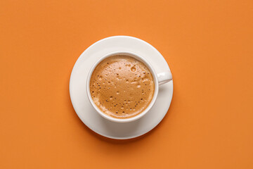 Cup of hot espresso on orange background