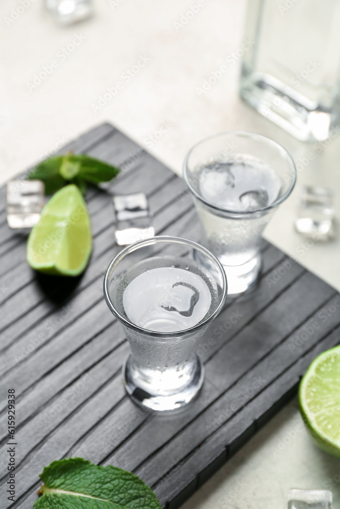 Glasses of cold vodka on light background