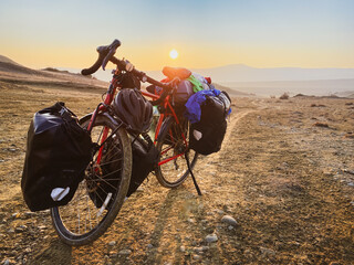 Loaded with bags red bicycle stands on side of road surrounded by mountains in countryside of VAshlovani national park. Bicycle touring holiday in Georgia