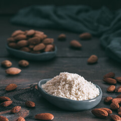 Wall Mural - Almond powder in gray trendy plate and almonds on dark wooden table. Almond flour and peeled kernel almonds. Copy space.