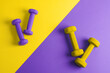 © Designpics - Sport flat lay composition with purple and yellow dumbbells on yellow and purple paper  background. Top view, horizontal orientation.