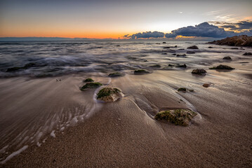 Sticker - early morning at sea shore with stones on the beach