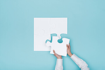 Woman assembling a jigsaw puzzle she is adding the last missing piece, solutions and challenges concept