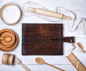 Wall Mural - empty brown wooden kitchen cutting board, rolling pin, sieve, wooden plates on a white wooden table, top view