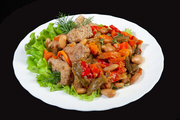 Porcelain plate with roasted meat and potatoes on a black studio background