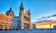 Madrid, Spain. Cathedral Santa Maria La Real De La Almudena At Plaza De La Armeria. Famous Landmark With Sunset Sunand. Street Lamps And Picturesque Sky With Clouds.