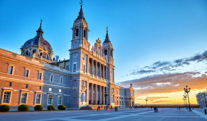 Wall Mural - Madrid, Spain. Cathedral Santa Maria la Real de la Almudena at Plaza de la Armeria. Famous landmark with sunset sunand. Street lamps and picturesque sky with clouds.
