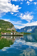 Sticker - Hallstatt, Austria. Touristic pleasure boat arriving to the old wooden dock at lake Hallstattersee among austrian Alps mountains. Picturesque summery landscape. Blue sky with clouds.