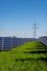 solar energy plant with power lines and wind turbines in the back seen in germany