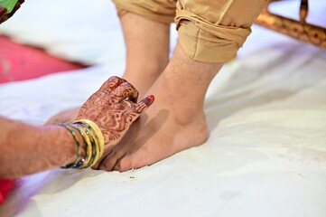 Wall Mural - feet of a Indian Groom. Hands of mother drawing symbol on groom legs. Marathi Wedding Rituals. Maharashtra Wedding. Indian Culture