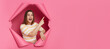 © sementsova321 - Excited positive brunette woman wearing striped top looking through ripped pink paper hole pointing at advertisement area saying wow empty space for promotion.