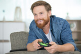 Fototapeta  - happy young addicted man playing video games in living room