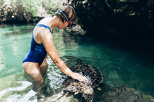 Young Girl Feeding Turtle In The Wild Pool. Zanzibar