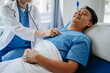 © Nuttapong punna - Doctor discussing treatment with male patient talking and laughing sitting on examination bed in modern clinic or hospital