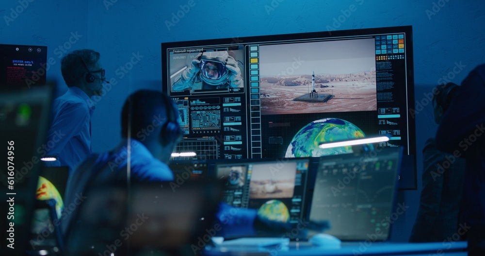 Flight control operators monitor space mission on computers in command center, have communication with astronaut. Team watch successful space rocket launch on big digital screen. Space exploration.