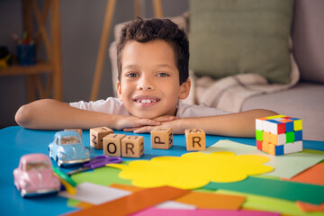 Poster - Photo of dreamy positive little boy dressed white t-shirt smiling playing toys indoors house home room