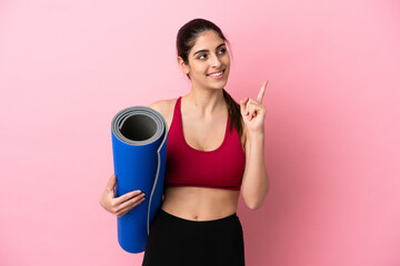 Wall Mural - Young sport caucasian woman going to yoga classes while holding a mat pointing up a great idea