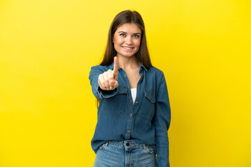 Wall Mural - Young caucasian woman isolated on yellow background showing and lifting a finger