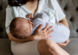 mother woman breastfeeding baby boy sitting on sofa.child infant newborn toddler eating breast milk
