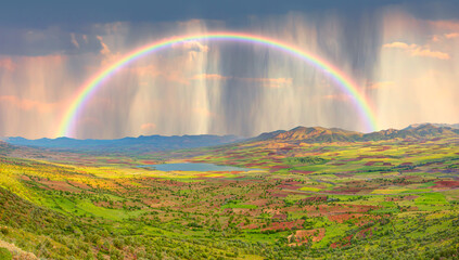 Poster - Beautiful blue lake landscape with a view of the mountains and a green valley and a rainbow in the clouds