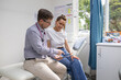 © Austockphoto - Male doctor holding a tablet  and talking to a female patient in the clinic