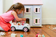 © Austockphoto - Young girl playing with a dollhouse and toy car