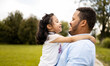 ©  Yistocking - A dark-skinned father plays with his daughter in an outdoor park. The African adult holds the little girl in his arms as they look at each other. Concept of African-American single-parent families.
