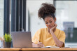 © Songsak C - A beautiful mixed race African American girl, student or businesswoman sitting at a desk and writing.