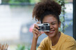 © Songsak C - A beautiful mixed race African American girl taking photos with a retro film camera.