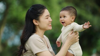 Wall Mural - mother holding and playing with baby newborn in the park with sunlight