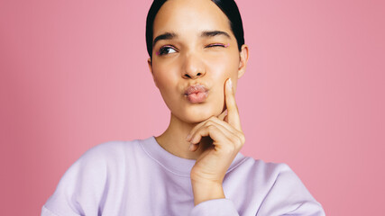 Wall Mural - Wink in the studio: Beautiful young woman making a flirty expression in a studio setting