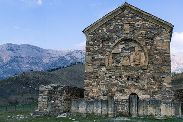 An ancient stone temple high in the mountains. Place of religious ceremonies. The old church on the background of the mountains. History and memory immortalized in stone.