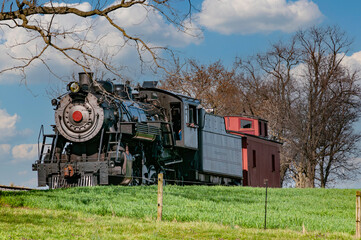 Sticker - A View of a Restored Steam Passenger Train Traveling Thru Open Fields and Meadows on a Blue Sky with Clouds Day