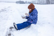 Little girl in winter clothes sledding and having fun on the snow