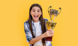 photo of glad teen champion girl with golden cup. teen champion girl isolated on yellow.