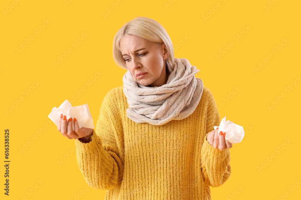 Ill mature woman with tissues on yellow background