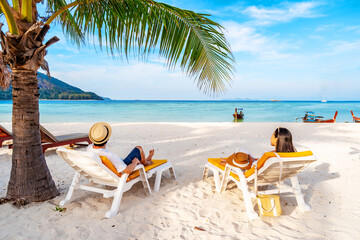 Young couple traveler relaxing and enjoying at beautiful tropical white sand beach with wave foam and transparent sea, Summer vacation and Travel concept