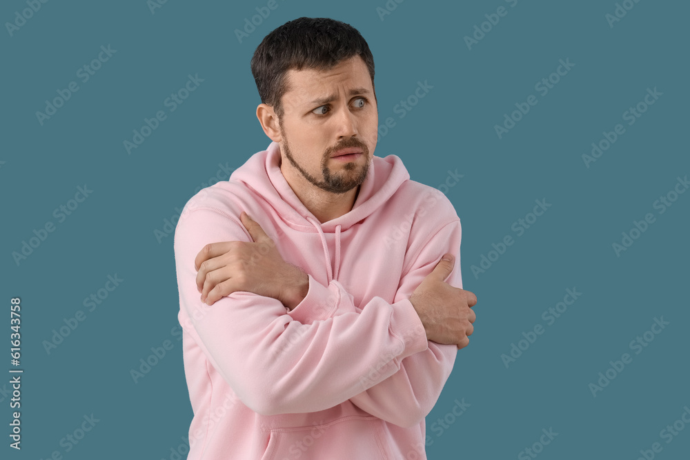 Young man having panic attack on blue background