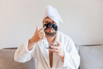 Wall Mural - funny bearded man applying black mask for skin care