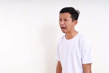 Wall Mural - Disappointed asian funny man standing while looking beside. Isolated on white background