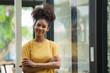© Songsak C - Young pretty African American standing and arms crossed near a window.