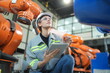 © FotoArtist - Mechanical engineers with robotic welder., Programming development technology work. Female industrial engineer working at automated AI robotic production factory