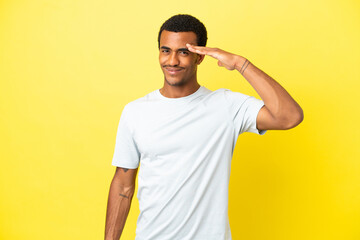 Wall Mural - African American handsome man on isolated yellow background saluting with hand with happy expression