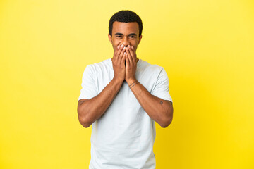 Wall Mural - African American handsome man on isolated yellow background happy and smiling covering mouth with hands