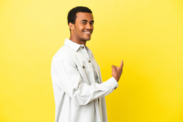 Wall Mural - African American handsome man on isolated yellow background pointing back