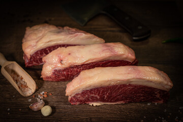 Organic machete or hanger butcher steak, near butcher knife with pink pepper and rosemary. Black background. Top view. side view