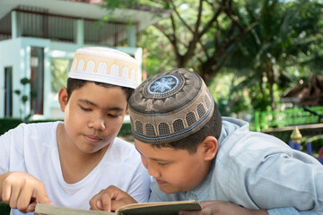 Young asian muslim or islamic boys sitting and doing exercise together at school park in the afternoon, soft and selective focus, lifestyle of children in muslim countries concept.