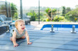 © Austockphoto - happy baby crawling on deck beside inground pool in backyard