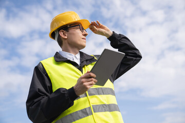 Poster - Engineer with digital tablet on a background of blue sky.
